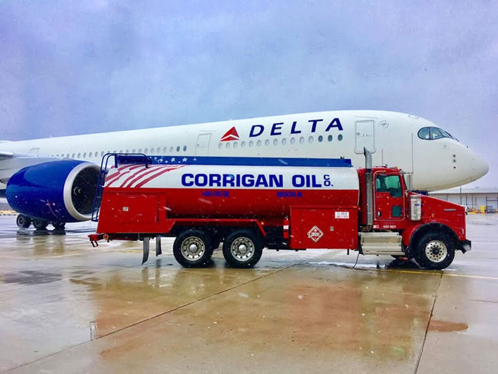 Corrigan Oil aviation fuel truck positioned beside commercial passenger aircraft for jet fuel delivery