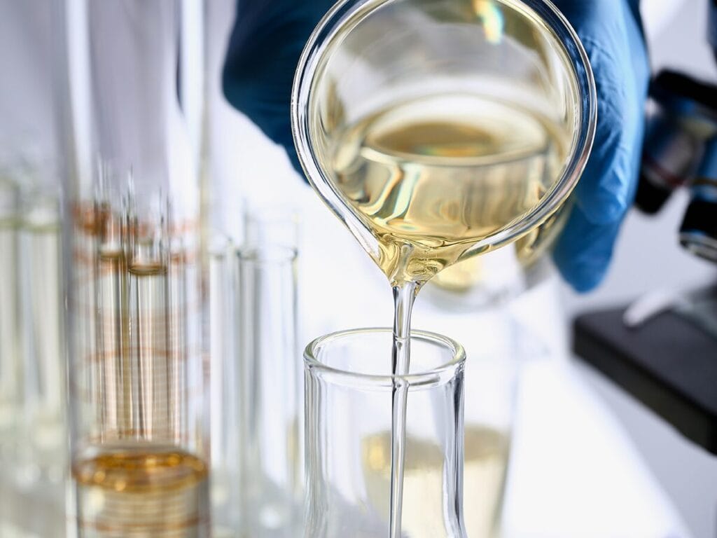 pouring oil into a flask in a lab