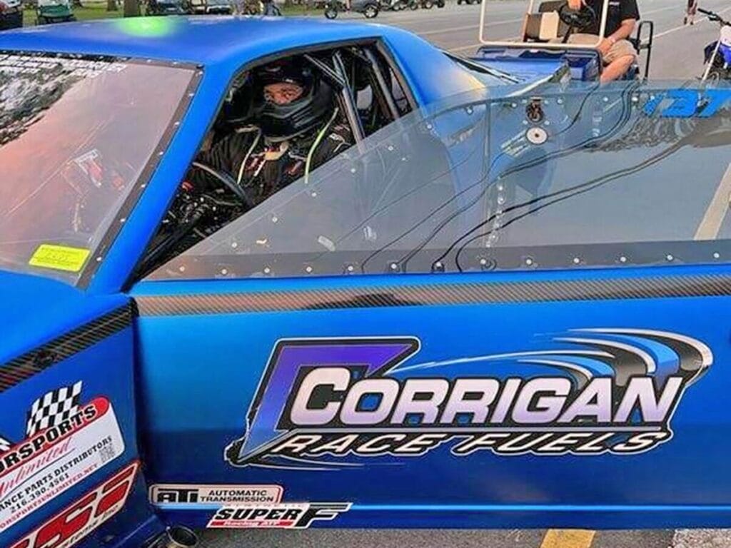 Corrigan Race Fuels branded race car driver preparing at track